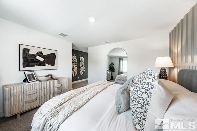 bedroom with arched walkways, carpet floors, visible vents, and baseboards