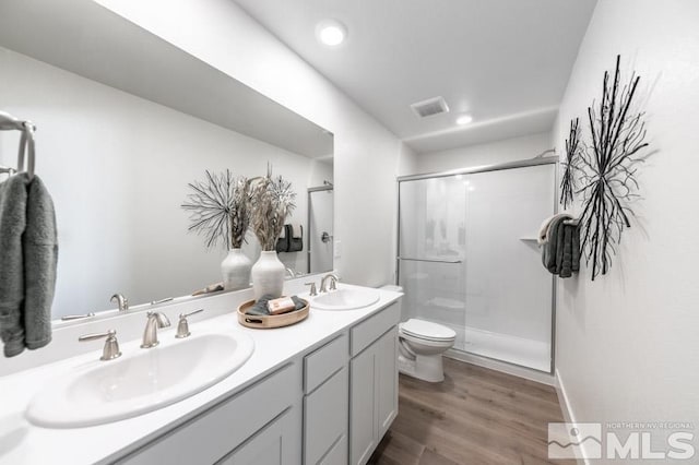 bathroom featuring wood finished floors, visible vents, toilet, and a sink