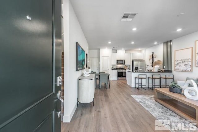 foyer entrance with baseboards, light wood-style flooring, visible vents, and recessed lighting