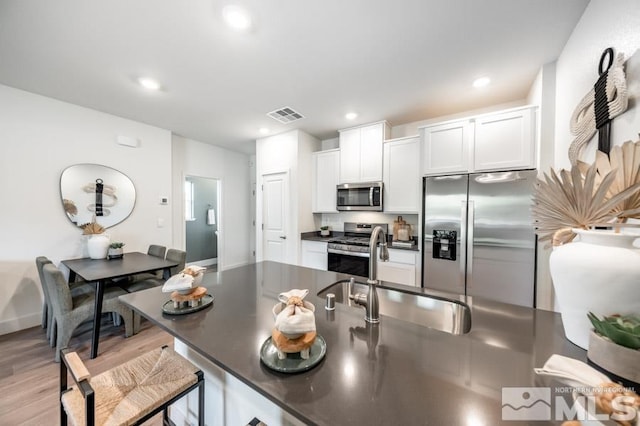 kitchen featuring dark countertops, stainless steel appliances, visible vents, and a sink