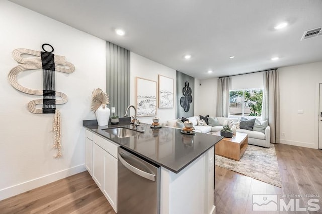 kitchen featuring a peninsula, a sink, dark countertops, visible vents, and dishwasher