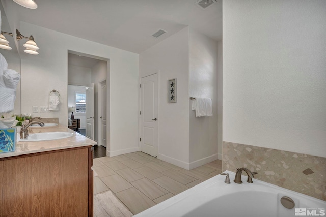 full bathroom featuring a bath, a sink, visible vents, and double vanity