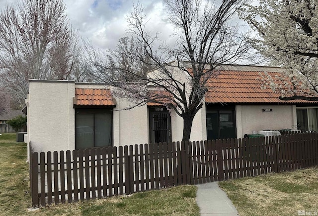 view of front of home featuring a fenced front yard, a tiled roof, and stucco siding