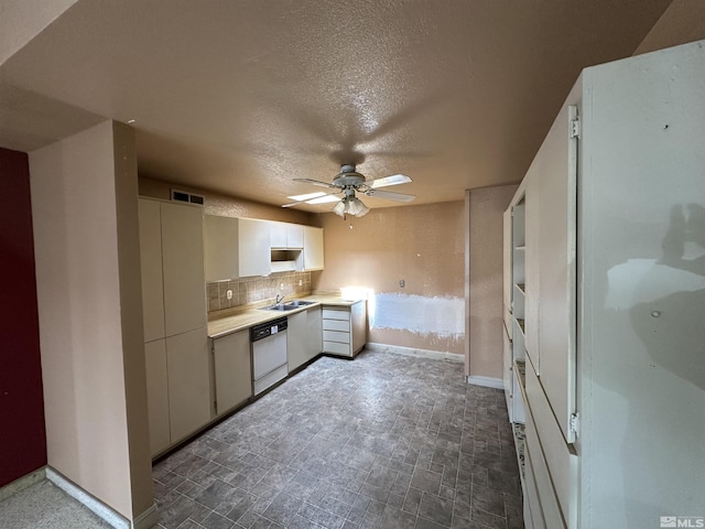 kitchen featuring white dishwasher, a sink, decorative backsplash, ceiling fan, and light countertops