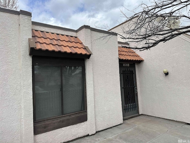property entrance with a tiled roof and stucco siding