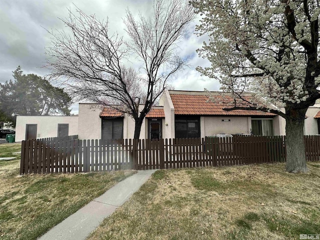 view of front of home featuring stucco siding, a tiled roof, and a fenced front yard