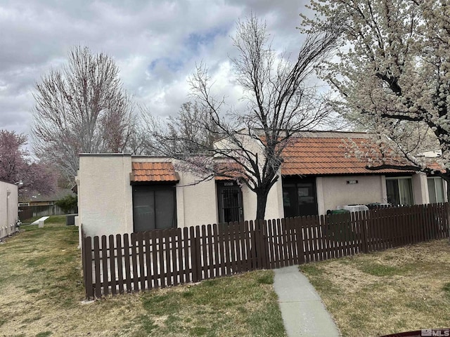 view of front of house with stucco siding, a tile roof, and a fenced front yard