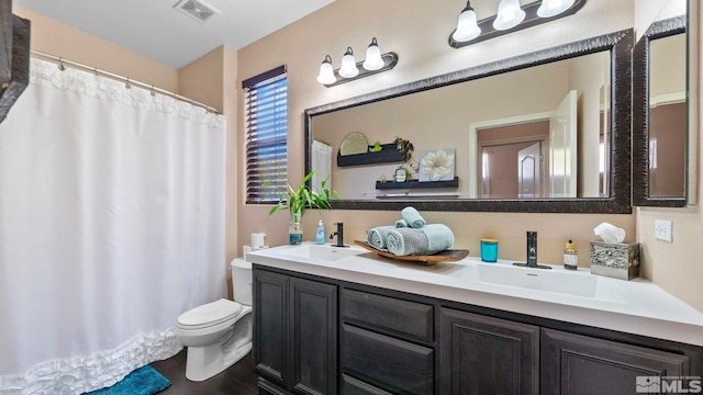bathroom featuring toilet, a sink, visible vents, and double vanity
