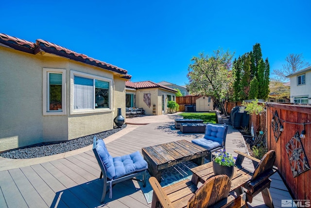 deck featuring a fenced backyard, an outbuilding, outdoor dining space, and a shed