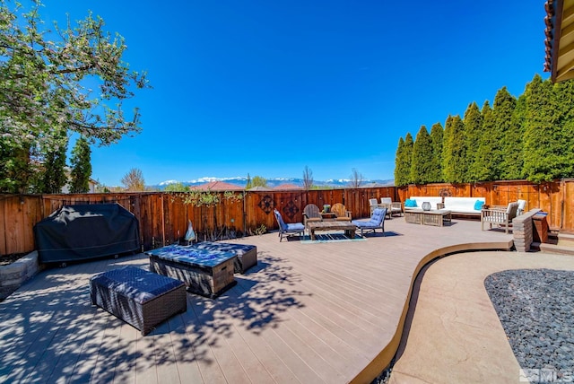 view of patio featuring grilling area, a wooden deck, fence, and an outdoor living space with a fire pit