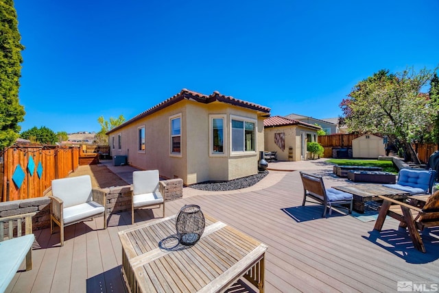 wooden terrace featuring a fenced backyard, a storage unit, and an outdoor structure