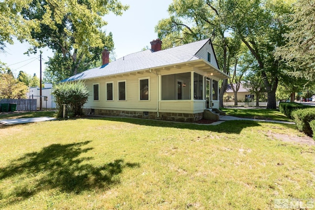 exterior space with a chimney, a sunroom, fence, and a yard