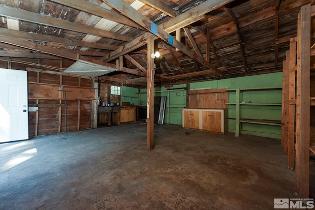 misc room featuring concrete floors, vaulted ceiling, and a garage