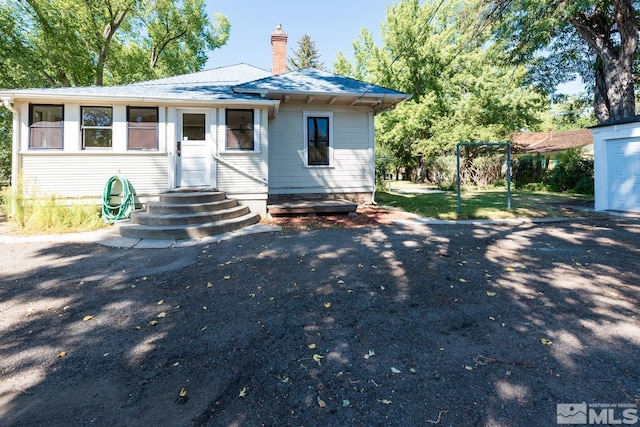 bungalow with a chimney and a shingled roof