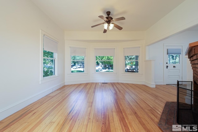 unfurnished living room featuring ceiling fan, baseboards, and wood-type flooring