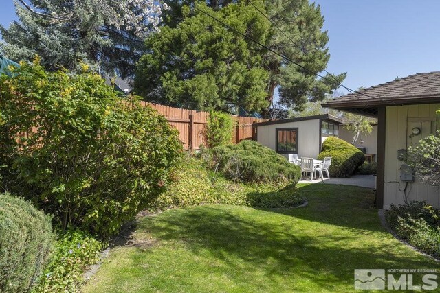 view of yard with an outdoor structure, fence, and a patio
