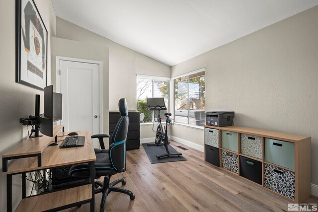office with lofted ceiling, baseboards, visible vents, and light wood-type flooring