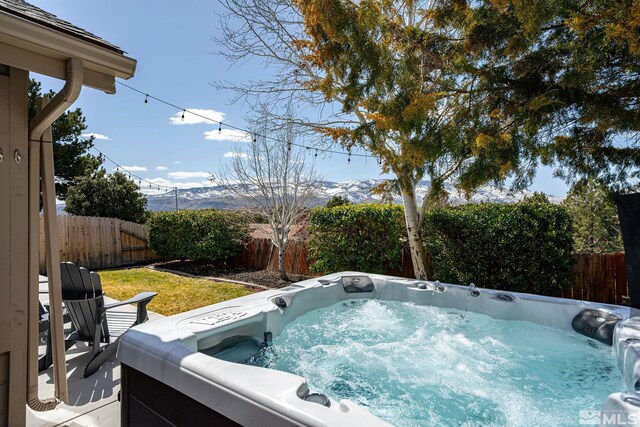 view of swimming pool with a hot tub, a fenced backyard, and a mountain view