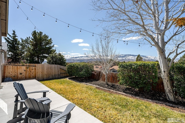 view of yard featuring a patio area, a fenced backyard, and a mountain view