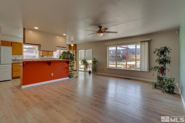 unfurnished living room featuring recessed lighting, plenty of natural light, light wood-type flooring, and ceiling fan