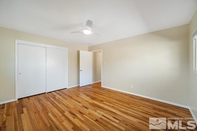 unfurnished bedroom featuring baseboards, light wood-style floors, and a closet