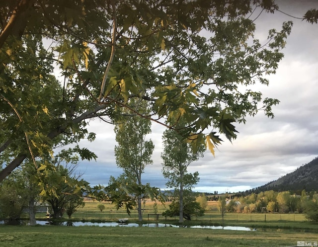 surrounding community featuring a water and mountain view, fence, and a yard