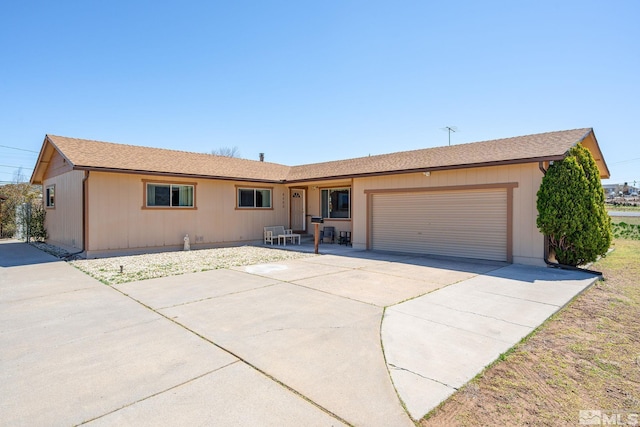 ranch-style house with an attached garage, driveway, and roof with shingles
