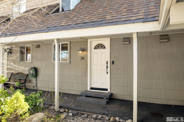 entrance to property featuring roof with shingles