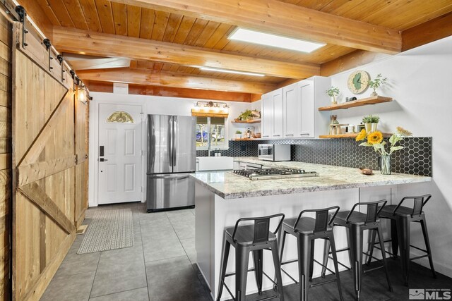 kitchen featuring a barn door, open shelves, wood ceiling, a peninsula, and appliances with stainless steel finishes