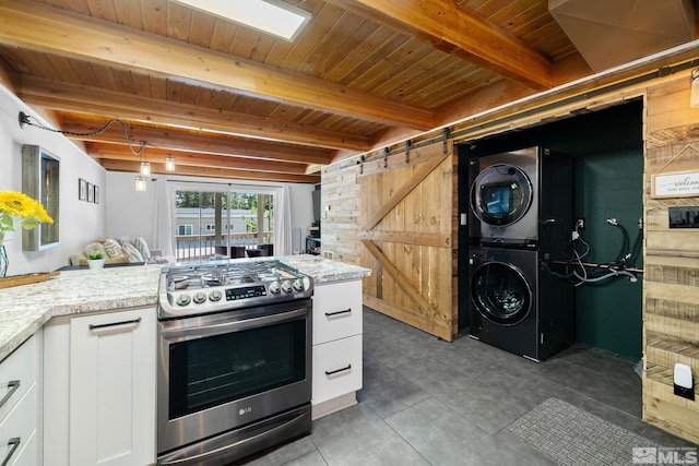 kitchen featuring a barn door, white cabinets, stacked washer / dryer, gas stove, and wood ceiling