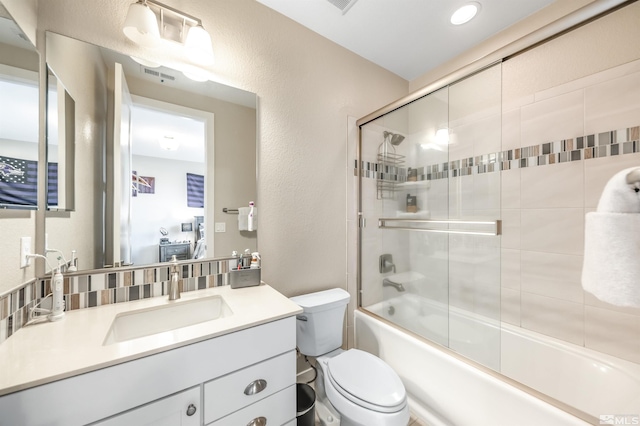 bathroom with vanity, bath / shower combo with glass door, toilet, visible vents, and a textured wall