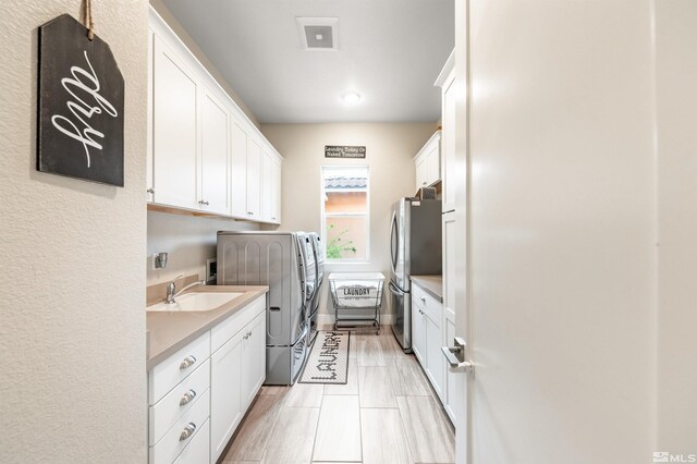 laundry room featuring recessed lighting, cabinet space, washer and clothes dryer, and a sink