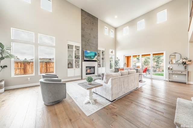 living room with hardwood / wood-style flooring, a wealth of natural light, a high ceiling, and a fireplace