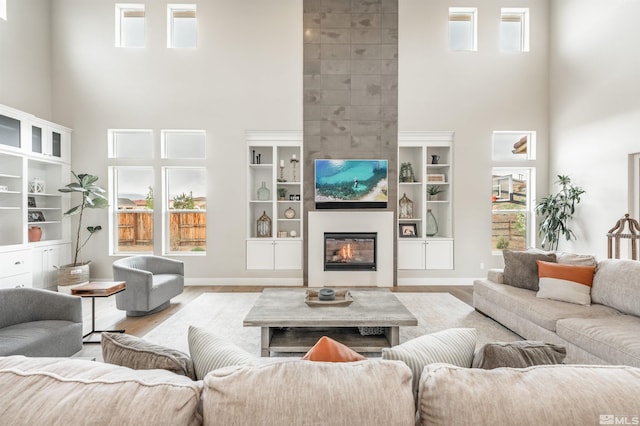 living room featuring a high ceiling, baseboards, wood finished floors, and a fireplace