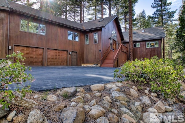 view of front facade with driveway, roof with shingles, and a garage