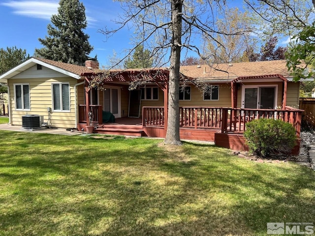 rear view of house with cooling unit, a lawn, fence, and a chimney