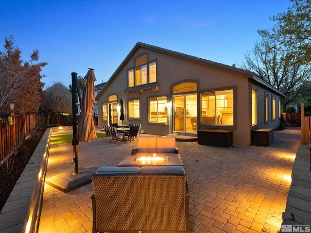 back of property with a fenced backyard, outdoor dining space, stucco siding, a patio area, and a fire pit