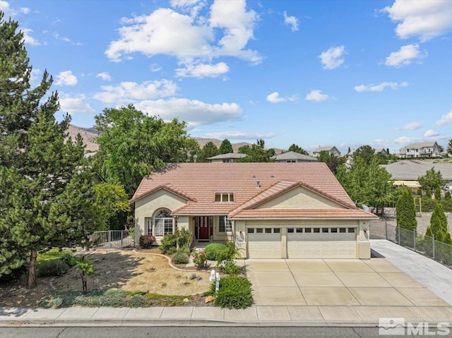 mediterranean / spanish-style house featuring stucco siding, fence, a tile roof, driveway, and an attached garage