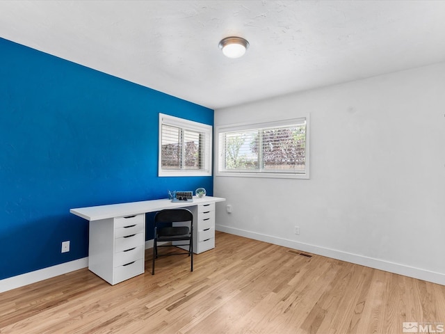 office with light wood finished floors, visible vents, and baseboards
