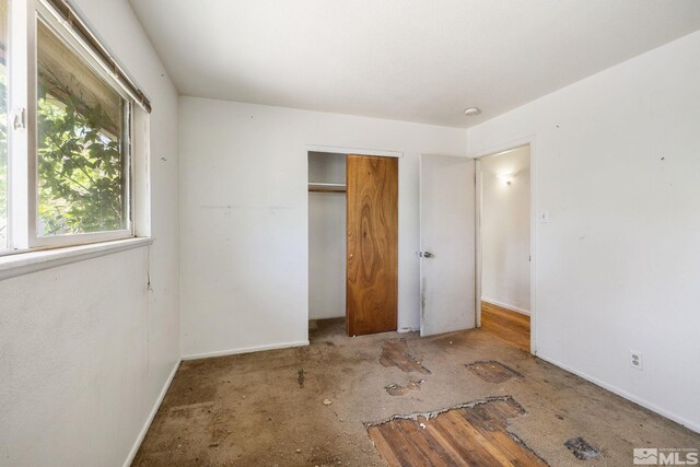 unfurnished bedroom with baseboards and a closet