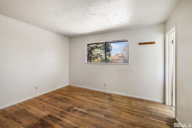 empty room featuring baseboards, visible vents, and wood finished floors