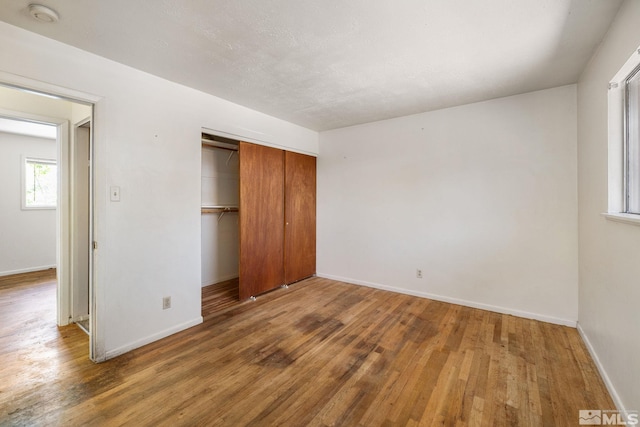 unfurnished bedroom with a closet, wood finished floors, and baseboards