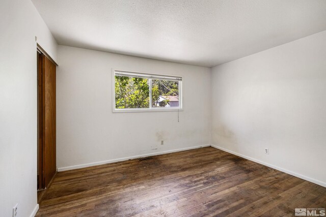 unfurnished bedroom featuring a closet, wood finished floors, and baseboards