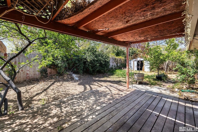 wooden deck featuring a fenced backyard, an outbuilding, and a storage shed