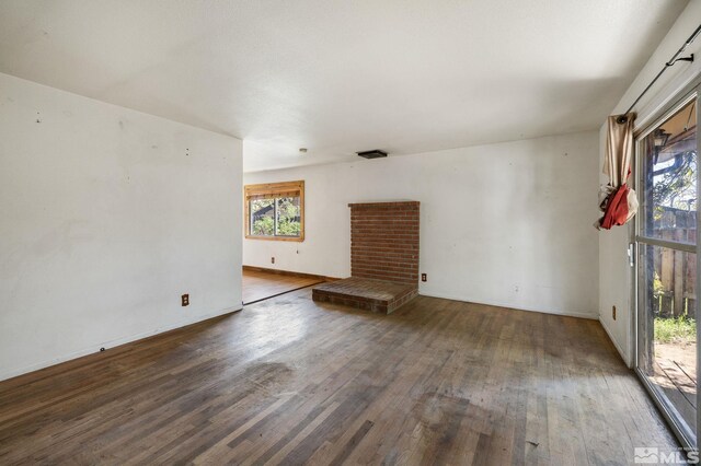 unfurnished living room featuring baseboards, wood finished floors, and a fireplace
