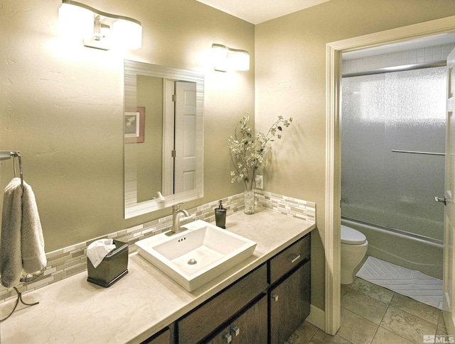 bathroom with vanity, toilet, tile patterned floors, enclosed tub / shower combo, and decorative backsplash