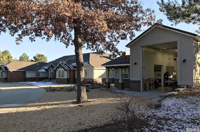 view of front facade featuring a patio, stucco siding, and brick siding