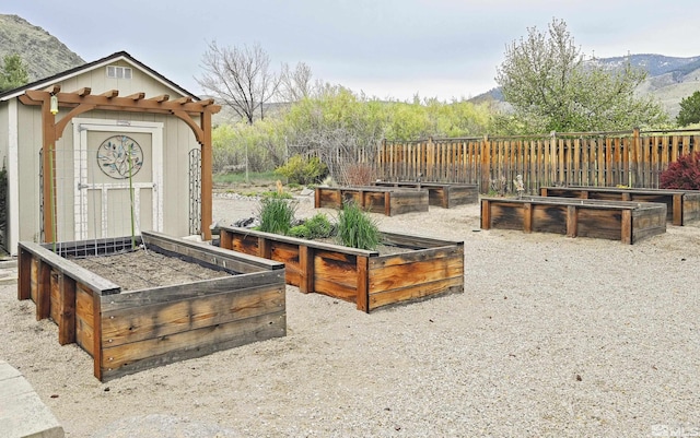 view of yard featuring a shed, a mountain view, an outbuilding, and a vegetable garden
