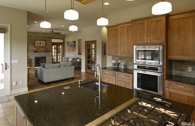 kitchen featuring stainless steel appliances, a ceiling fan, a sink, and tasteful backsplash