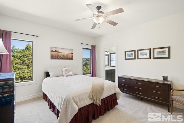 bedroom with ensuite bathroom, a ceiling fan, light carpet, and baseboards